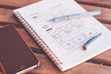 Notebook with website UX design next to mobile phone